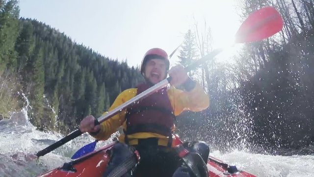 An active male kayaker rolling and surfing in rough water. Slow motion.