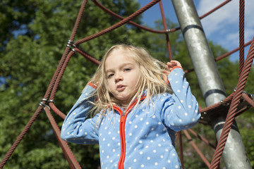 Pretty blond girl playing on rope of red web in summer © Petr Bonek