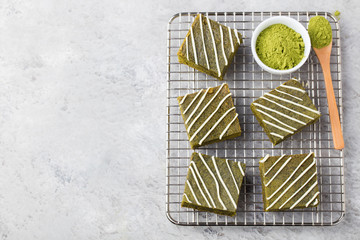 Matcha green tea brownie cake with white chocolate on a cooling rack Grey stone background Top view...