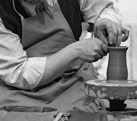 Potter with the hand lathe during production of a pot with clay