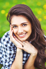 Fototapeta premium Beautiful young woman outdoors. Enjoy nature. Healthy smiling girl lying on green grass.