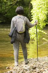 mature caucasian woman hiking , hike in the river ; traveler with backpack on beautiful landscape
