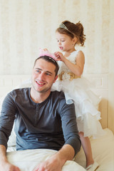 Cute girl putting a crown on her father head