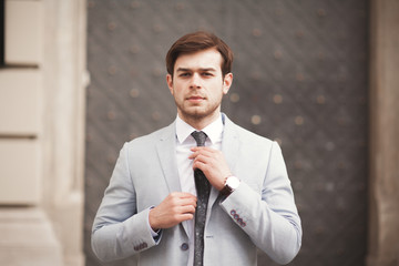 Young stylish businessman adjusting his suit, neck tie