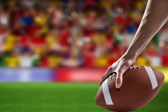 Composite image of man holding a american football ball 