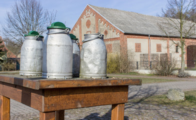 milk cans / Milk cans stand on a wooden table in the village