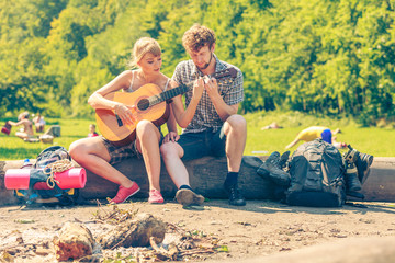 Young couple camping playing guitar outdoor