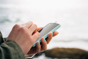 Female hands holding a blue cell phone with the connected headph