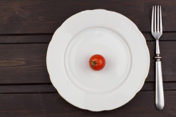 Very strict diet. Dietary vegetable diet. Tomatoes on a plate. Slimming diet. White plate with tomato on dark table.
