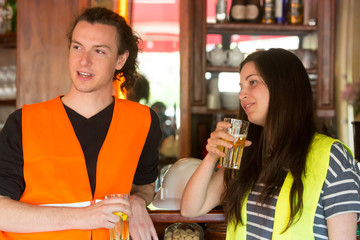 Two young civil engineers, a man and a smiling girl, drinking beer during work break