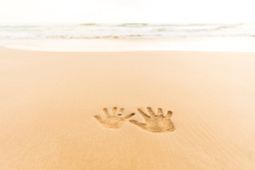 Love handprint with wedding ring on the sand