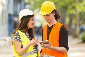 Two young civil engineers working on construction site using tablet computer
