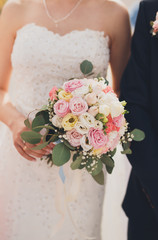 Pretty good wedding bouquet of various flowers in hand