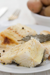 boiled cod fish with black pepper on white plate and potato in bowl
