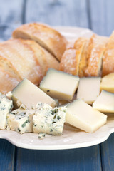 cheese with bread on white dish on blue wooden background