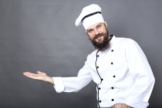 Studio shot of a young chef invinting over gray background