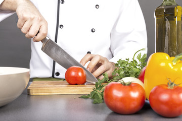 Chef's hands cutting red fresh tomato