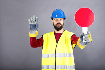 Young construction worker with hardhat stopping traffic