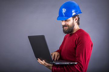 Happy young engineer with hardhat standing while working on his