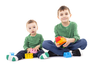 Two brothers playing with colorful cubes on the floor
