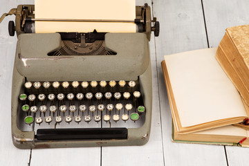 Retro typewriter and old vintage books on white wooden backgroun