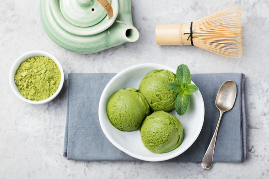 Green tea matcha ice cream scoop in white bowl on a grey stone background. Copy space Top view