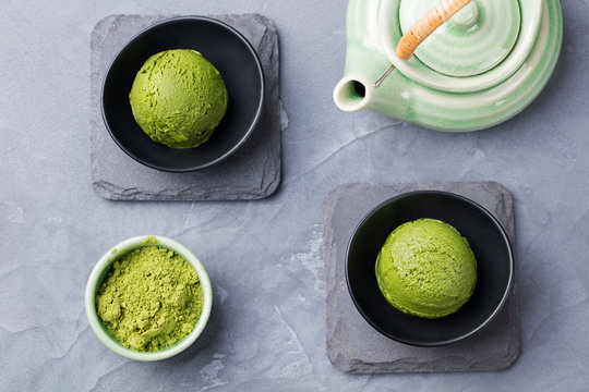Green tea matcha ice cream scoop in bowl on a grey stone background Top view