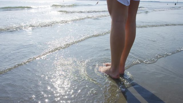 4K Female walking into the surf of the sea, in slow motion