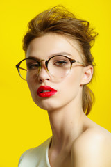 Portrait of a beautiful girl in glasses on a yellow background in the studio