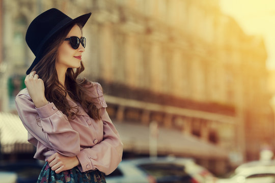 Outdoor portrait of young happy lady posing on street. Model wearing stylish clothes. Girl looking aside. Sunny day. Female fashion. City lifestyle. Toned style instagram filters. Copy space for text