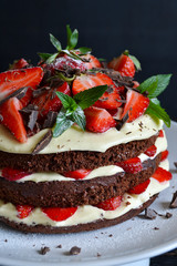Naked cake with cream, decorated with strawberry, mint and choco
