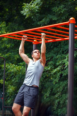 Muscular man doing pull-ups on horizontal bar