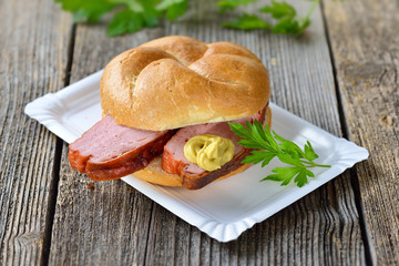 Streetfood bayerisch: Warme Leberkässemmel mit Senf auf Pappteller - Bavarian street food: roll...