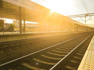 Peron kolejowy przy zachodzie słońca, zachodzące słońce wpada w obiektyw