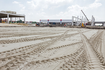 Tire tracks of a big vehicle are on the sand in direction of bui