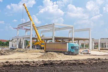 Obraz premium Mobile crane is unloading concrete joist from truck trailer.