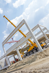 Mobile crane is operating and lifting concrete joist. Landscape