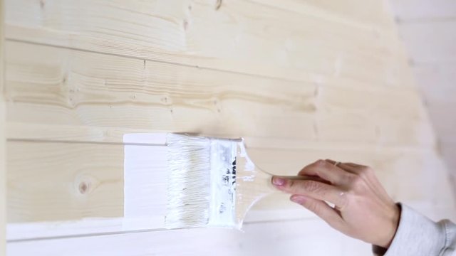 Woman painting wooden slot and key boards in white color with brush
