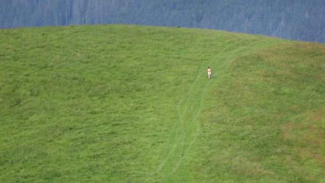 Female make selfie far on mountain meadow. Small people.