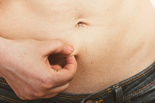 Human holding pinching fat body belly.