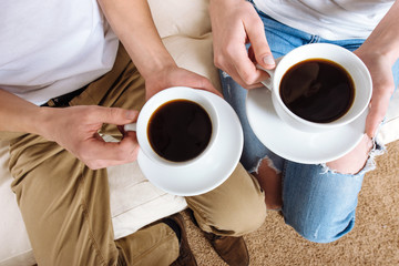 hands of young lovers holding a cup of coffee.