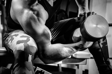 The athlete doing exercises for hands with dumbbells