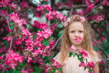 Obraz na płótnie Canvas Portrait of little girl in beautiful blooming apple garden outdoors