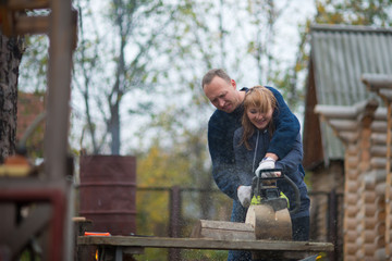 couple in autumn home garden sawing wood