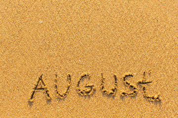 August - word inscription on the gold sand sea beach.