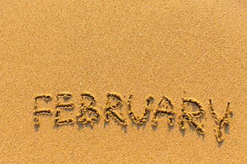 Fototapeta premium February - word inscription on the gold sand sea beach.