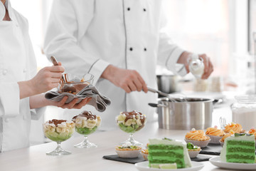 Chefs making and pouring chocolate  sauce over a fruit dessert.