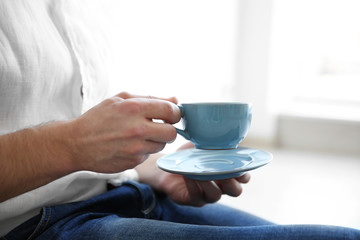 Fototapeta na wymiar Man holding blue cup of coffee, close up