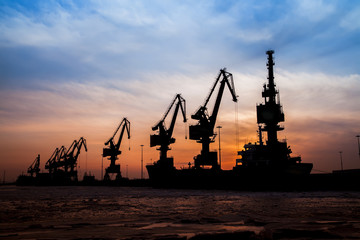 Obraz premium In the evening, the silhouette of port cranes
