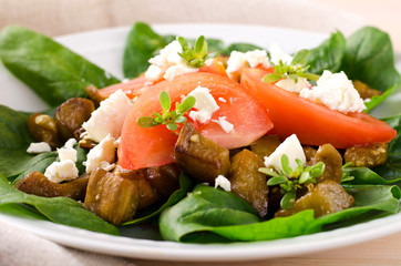 Eggplant salad with tomatoes, feta cheese, spinach and greens
